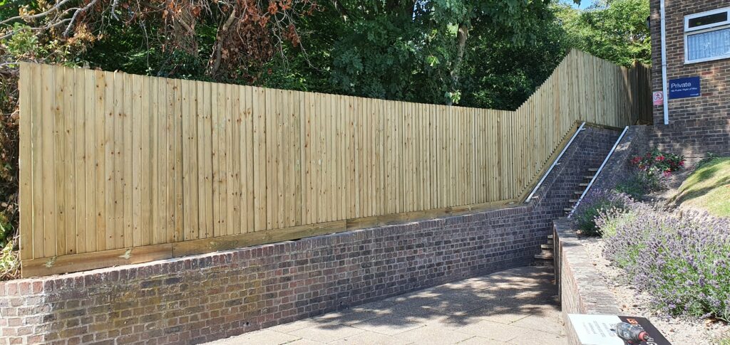 timber security fencing installed with gates behind sloped brick wall dover